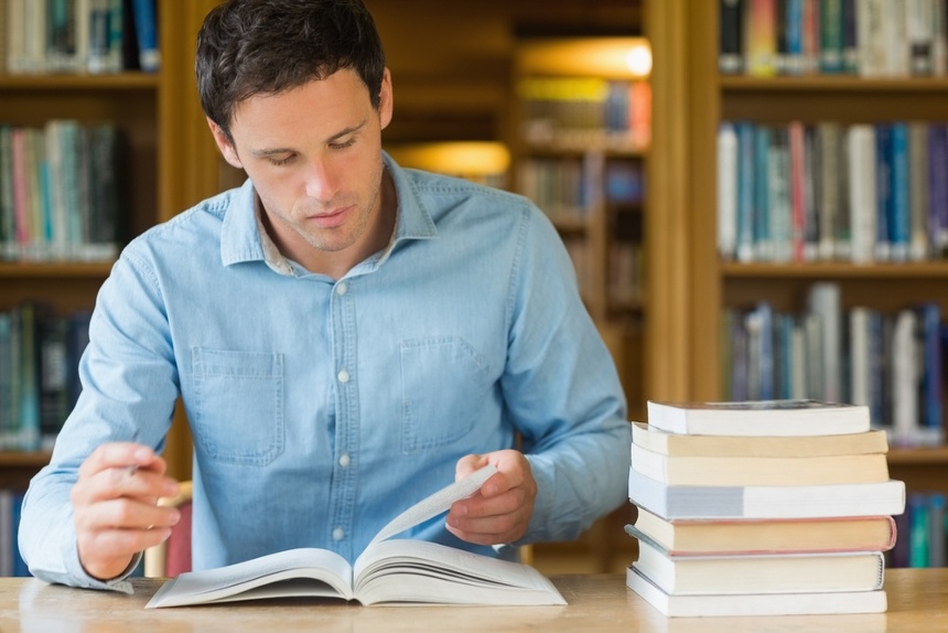 Serious mature male student studying at desk in the library