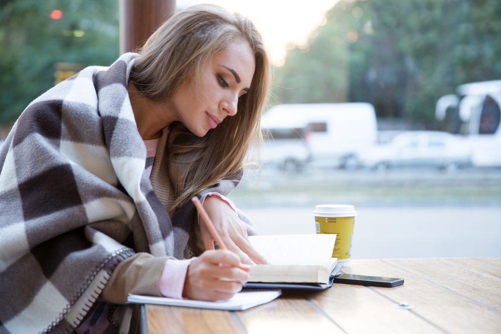 Portrait of a charming girl doing homework in cafe